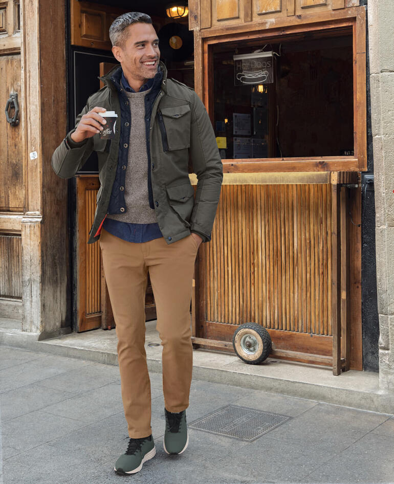 Veste dʼaviateur en nylon Schott NYC Homme portant des sneakers recyclés, buvant un café.