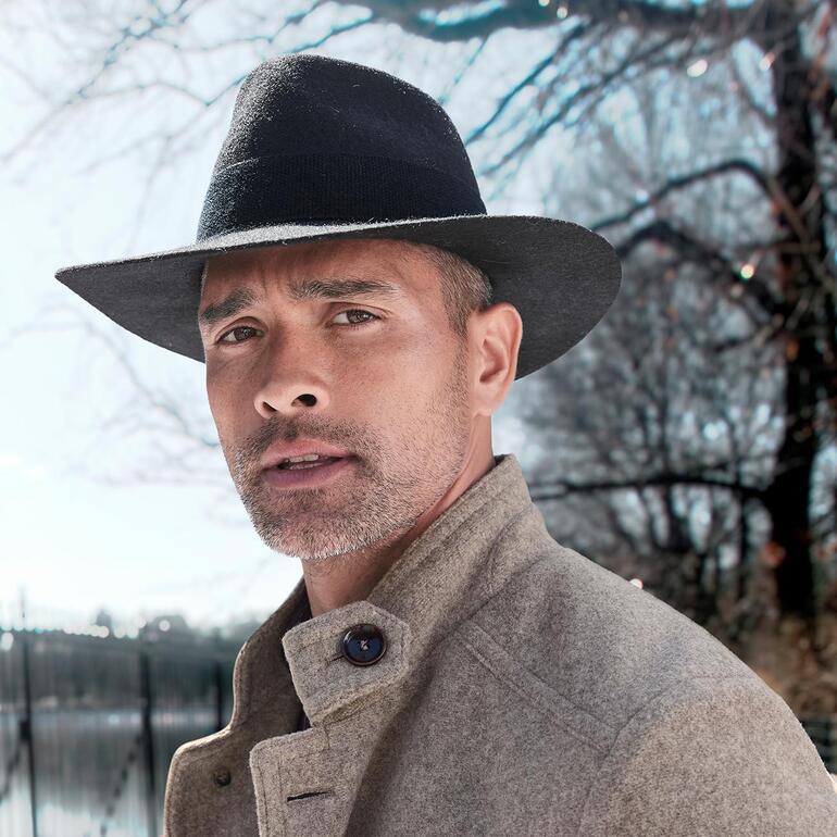Chapeau en feutre et alpaga Homme avec un chapeau en alpaga noir et un manteau gris, en extérieur.