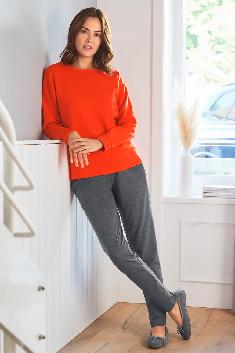 Ballerines en laine bouillie Gottstein Femme en sweat-shirt rouge et pantalon de jogging gris adossée à un escalier.