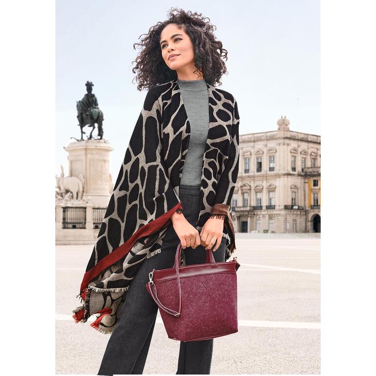 Poncho réversible Ancini avec différents motifs, porté par une femme en ville.