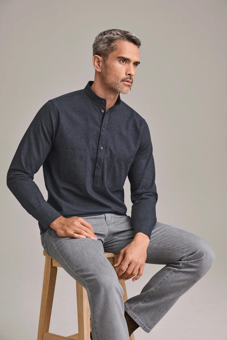 Homme en chemise Nehru en flanelle de coton gris foncé assis sur une chaise.