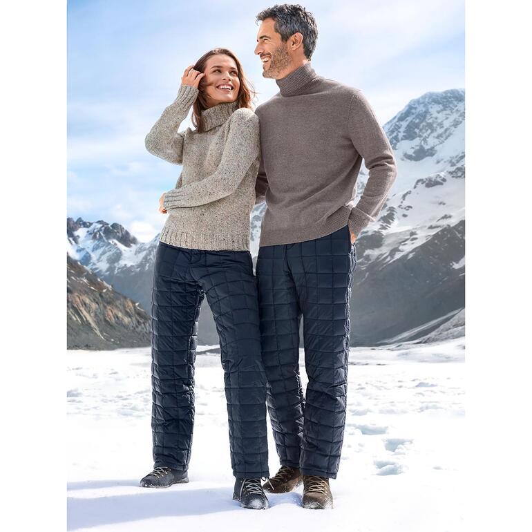 Un couple de modèles portant une doudoune et un pantalon dans un paysage montagneux