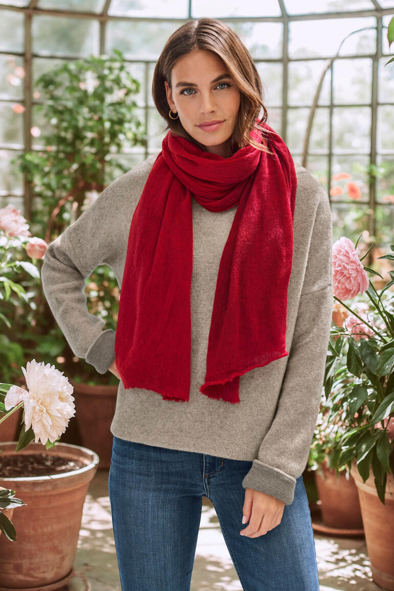 Femme portant une écharpe en cachemire rouge dans un jardin.