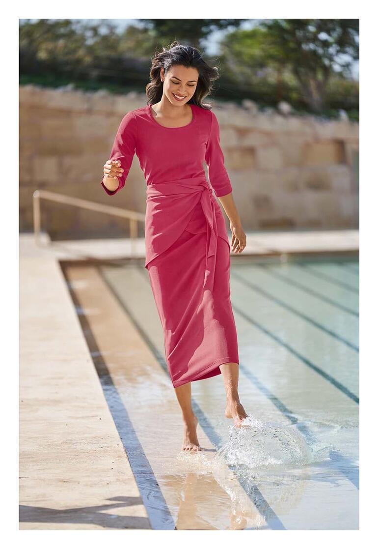Femme en robe rose près de la piscine
