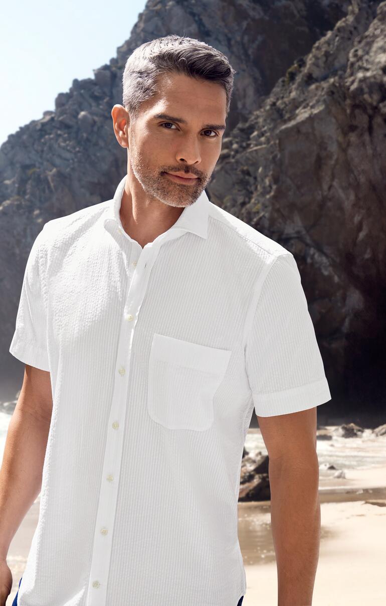 Homme en chemise seersucker blanche à l'extérieur avec des rochers en arrière-plan.