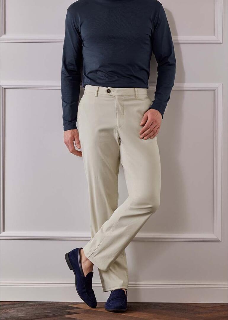 Homme en pantalon léger debout sur une balustrade en bois.