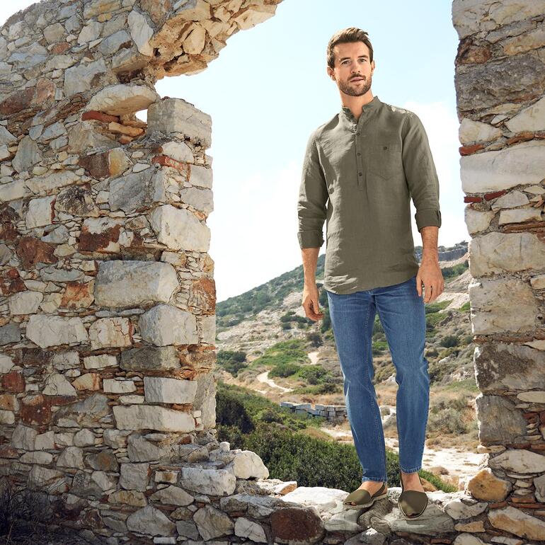 Homme portant des Eco Avarcas de Menorca devant des murs historiques dans un environnement ensoleillé.