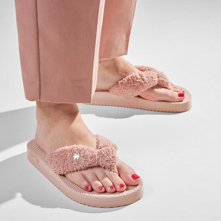 Femme portant des tongs en éponge roses avec vernis à ongles rouge.