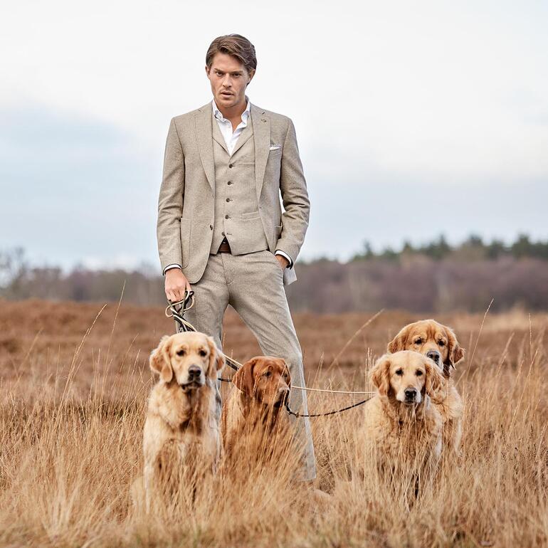Homme en veste soft donegal avec trois chiens à l'extérieur.