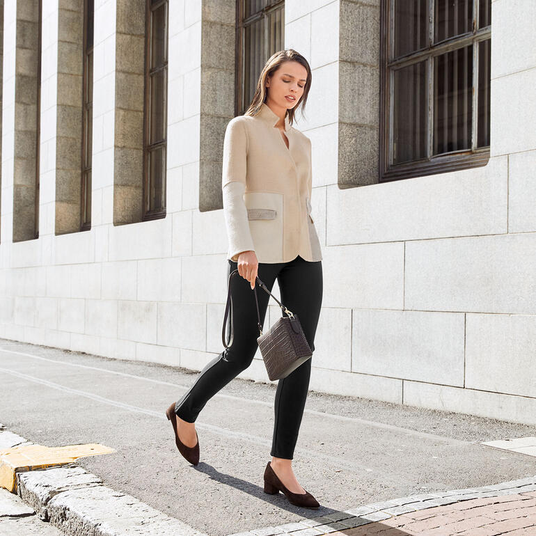 Brun Femme en pantalon noir et haut beige, marchant dans la rue.