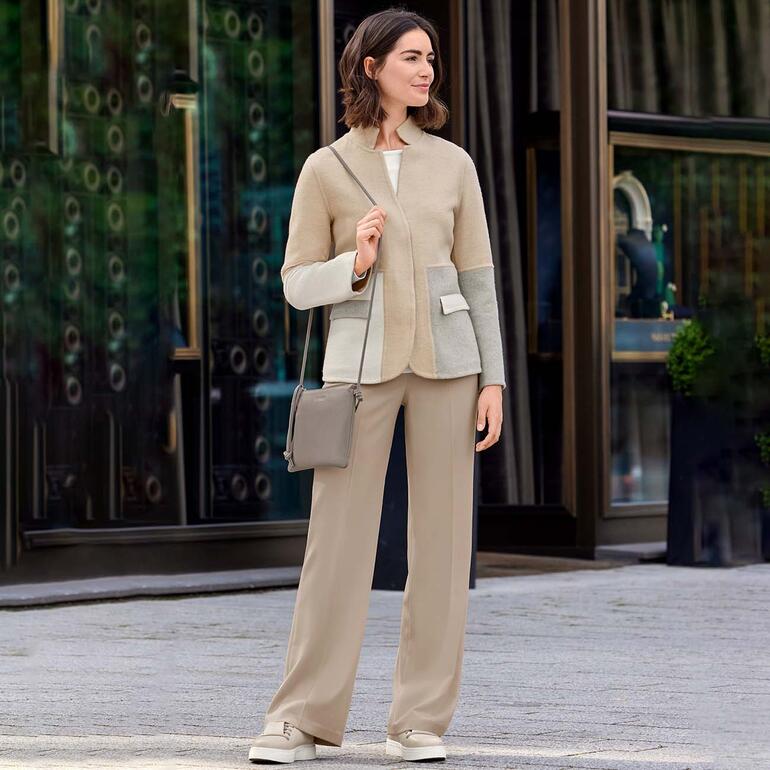 Femme portant un sac crossbody 3-en-1 beige, devant un bâtiment moderne.