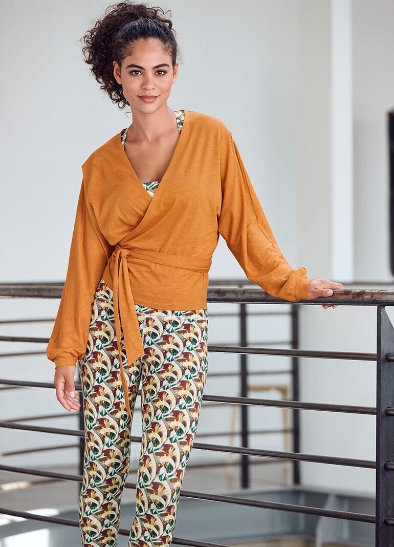 Femme en tenue Mandala avec un gilet croisé et des leggings, souriante.