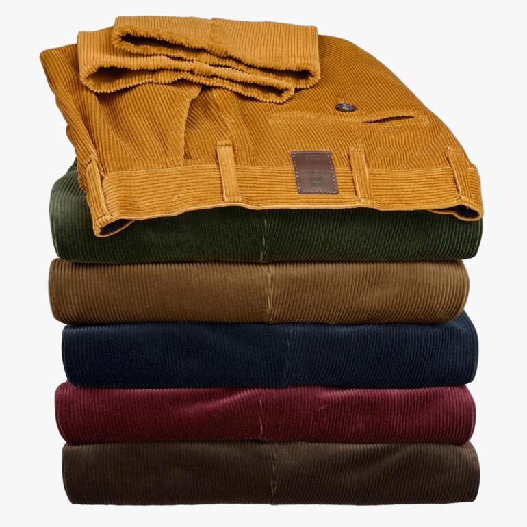 Pantalons en velours côtelé Kindermann empilés dans différentes couleurs, soigneusement empilés.