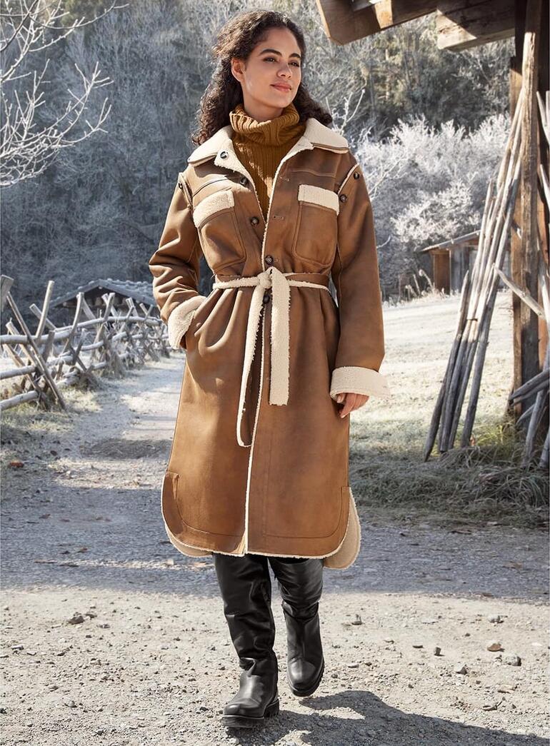 Femme dans un manteau en teddy marron avec une ceinture dans un environnement hivernal.
