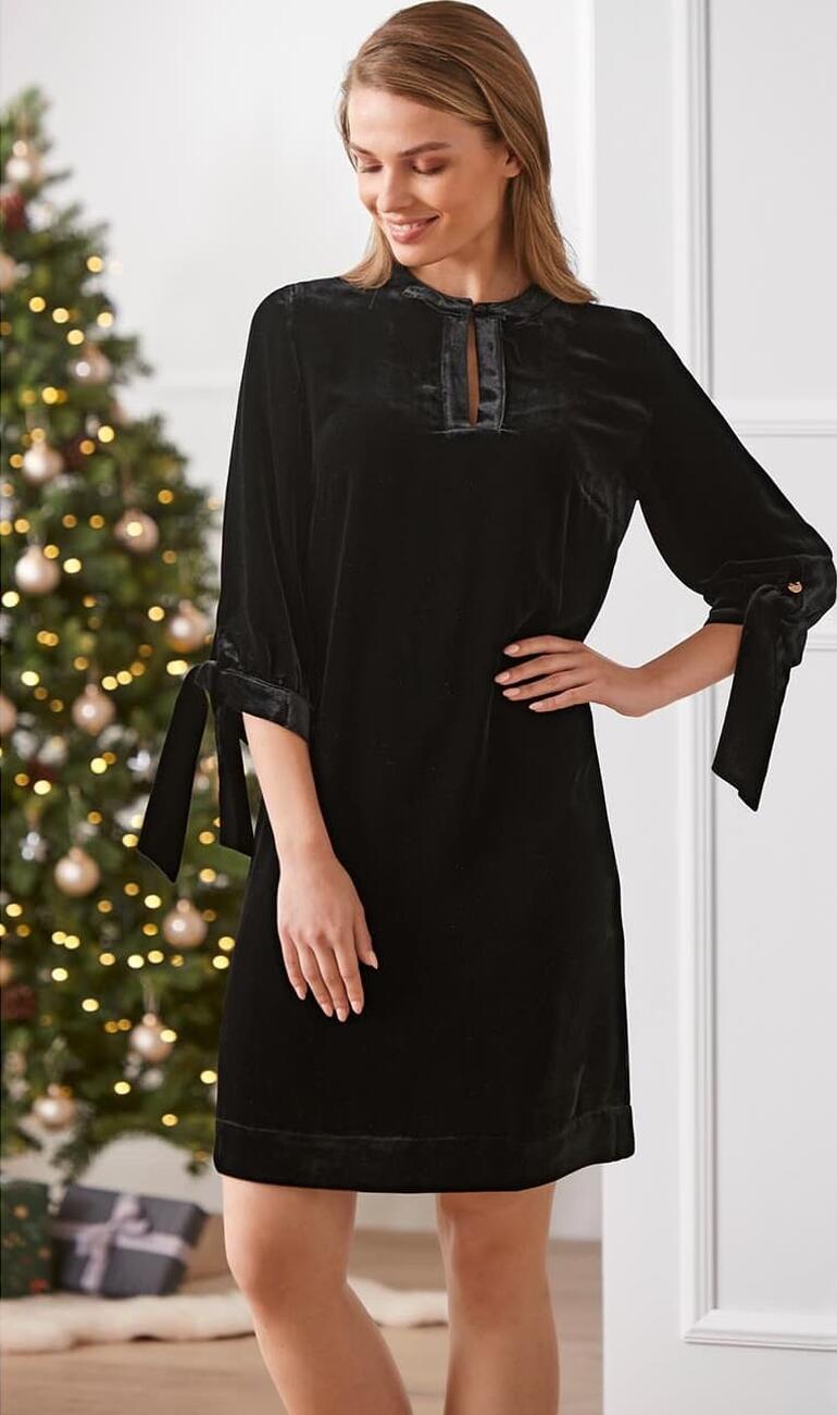 Robe tunique en velours Robe tunique femme en velours de soie noire avec des manches à nœud, décoration de Noël en arrière-plan.
