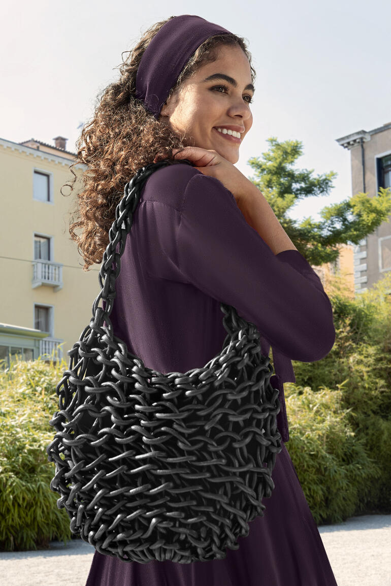 Noir Sac tressé noir brillant Alienina, porté par une femme.