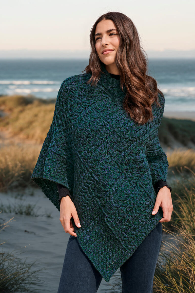 Bleu atlantique Femme en poncho Aran posant sur la plage.