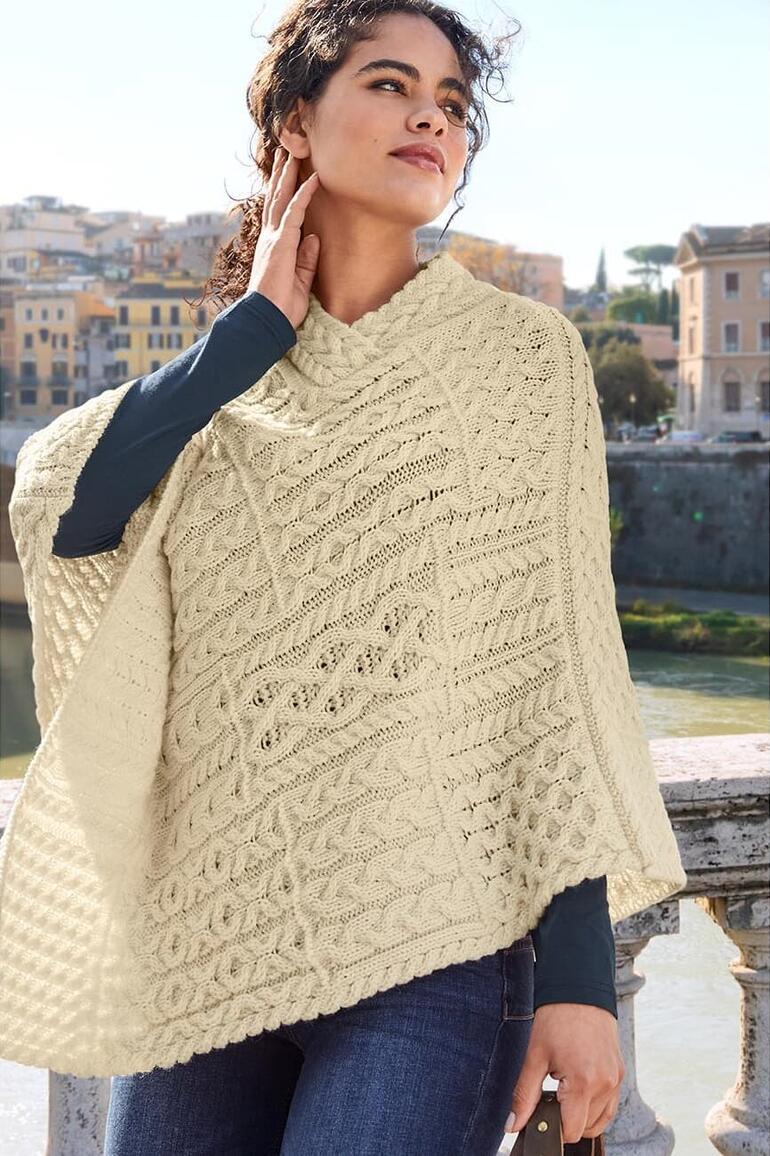 Femme en poncho clair sur un pont avec des jeans décolorés.