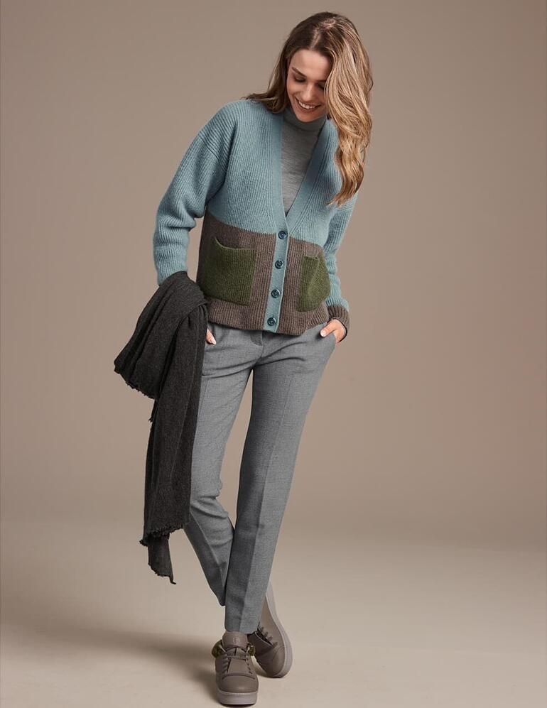 Taupe Femme en cardigan vert avec des baskets en peau de mouton Chaaya sur fond marron.