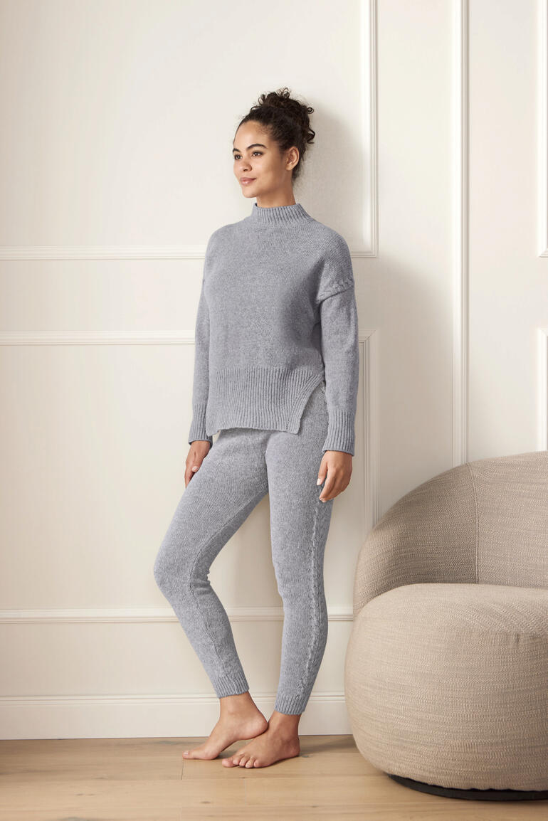 Femme portant un pull en merinos gris et un legging dans une pièce lumineuse