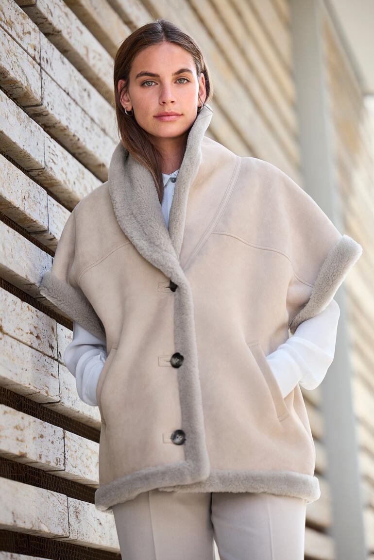 Gilet en peau de mouton beige avec col montant, porté par une femme.