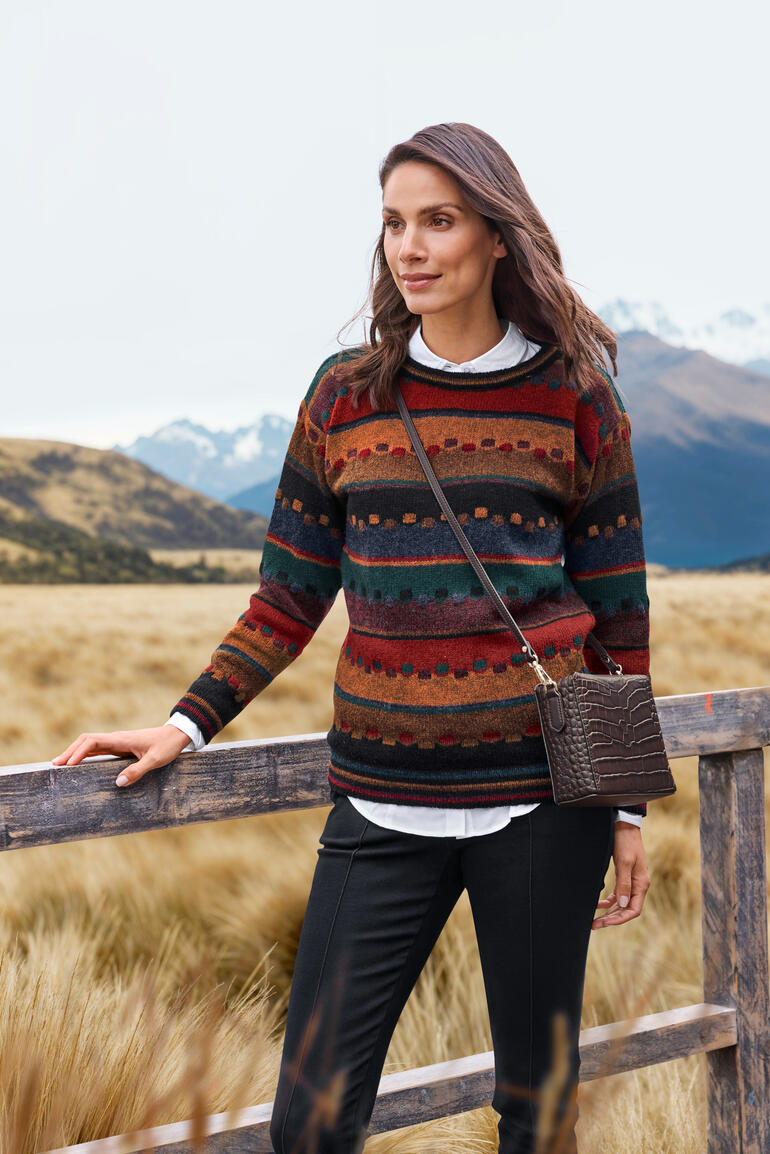 Femme portant un pull coloré avec un motif automnal dans un environnement naturel.