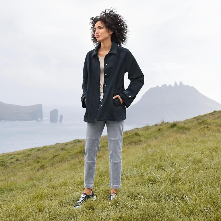 Jogging à rayures et en denim Stehmann Femme portant une veste de pluie noire Ilse Jacobsen se tenant sur l'herbe.