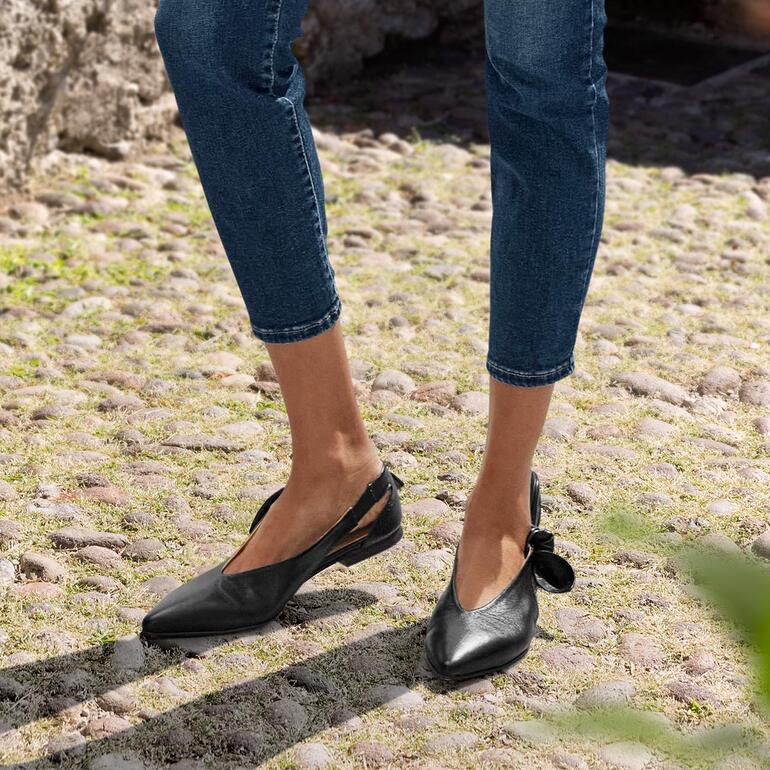 Ballerines noires 2-en-1 de face, portées par une femme en jeans.