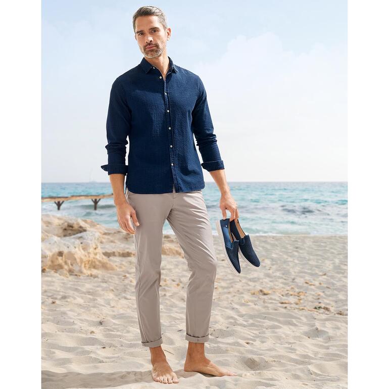 Beige clair Homme en chemise en jeans Seersucker foncé devant un bâtiment traditionnel.