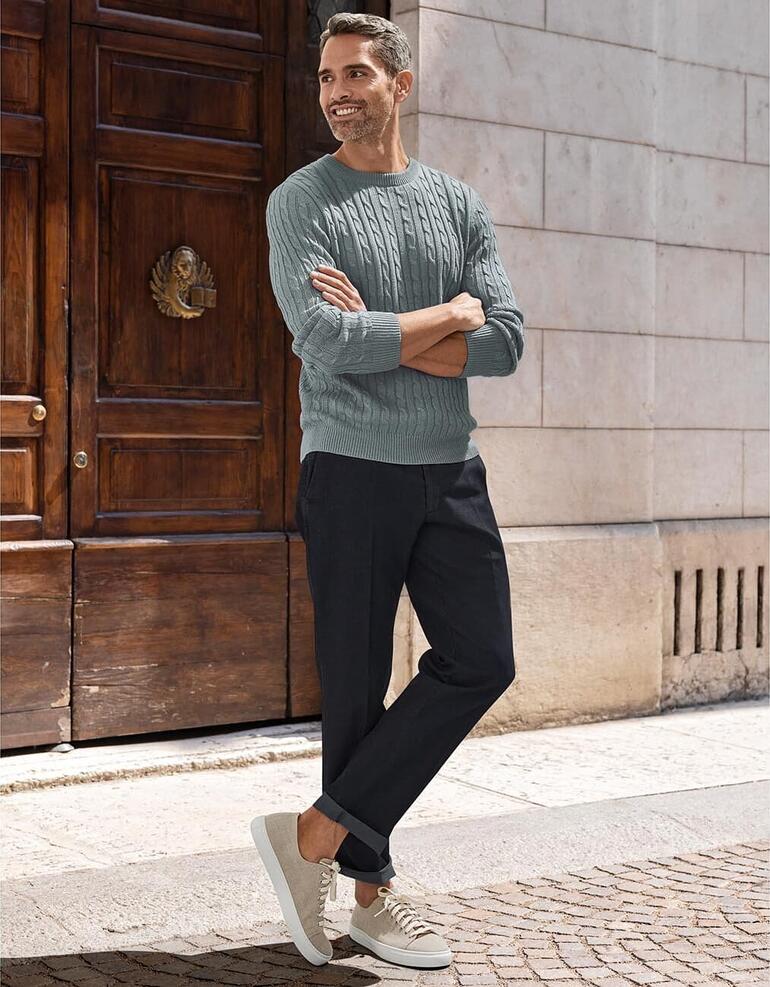 Gris Homme portant un pull en lin Carbery devant une vieille porte en bois.