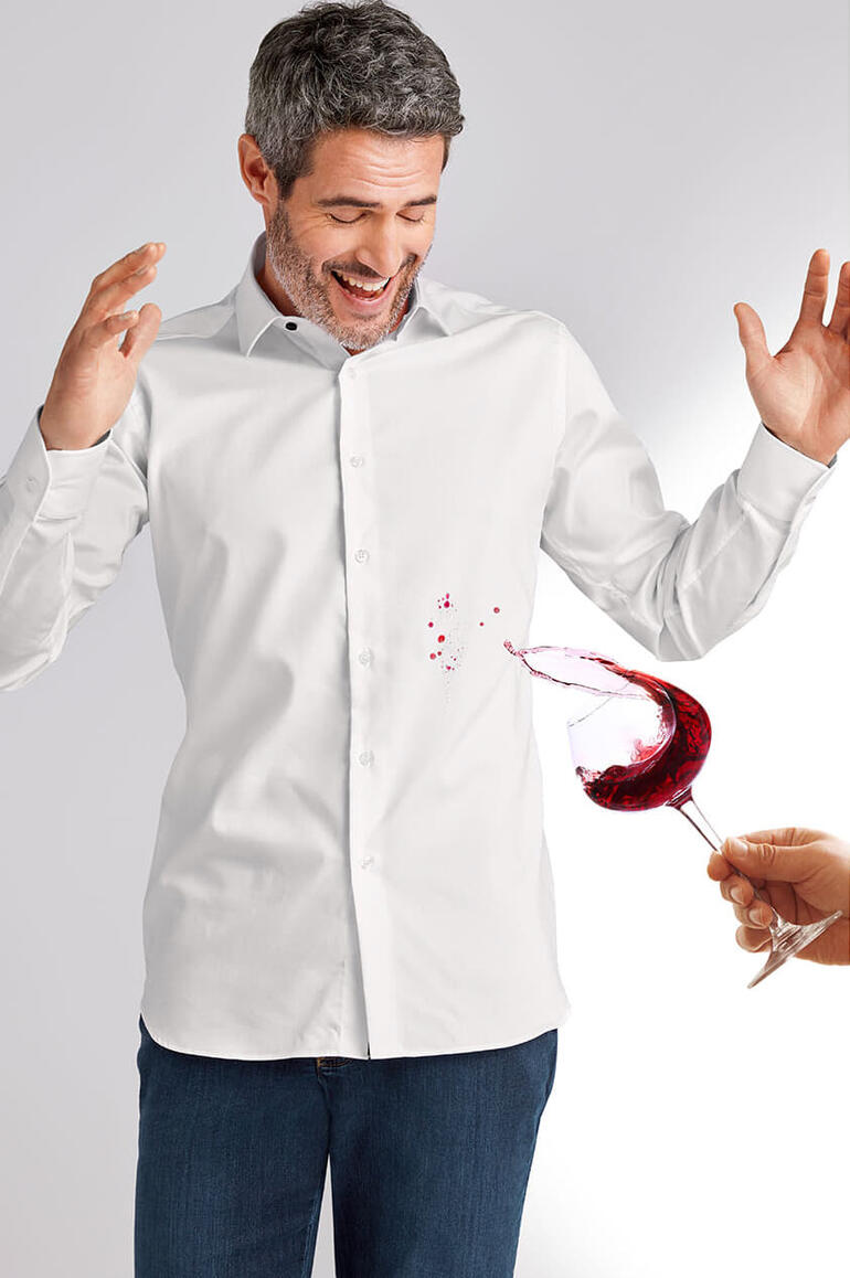 Homme en chemise blanche, joyeux avec du vin rouge renversé.