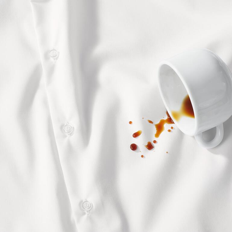 Chemise blanche avec une tache de café et une tasse à côté.