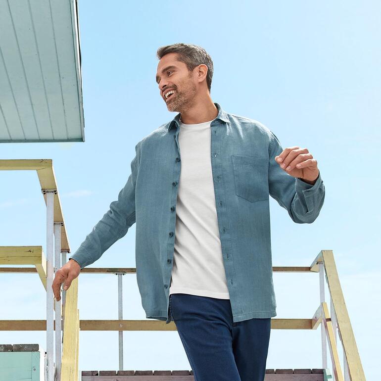 Homme portant une chemise en Hanf-SeaCell™ bleu clair, souriant en descendant un escalier.