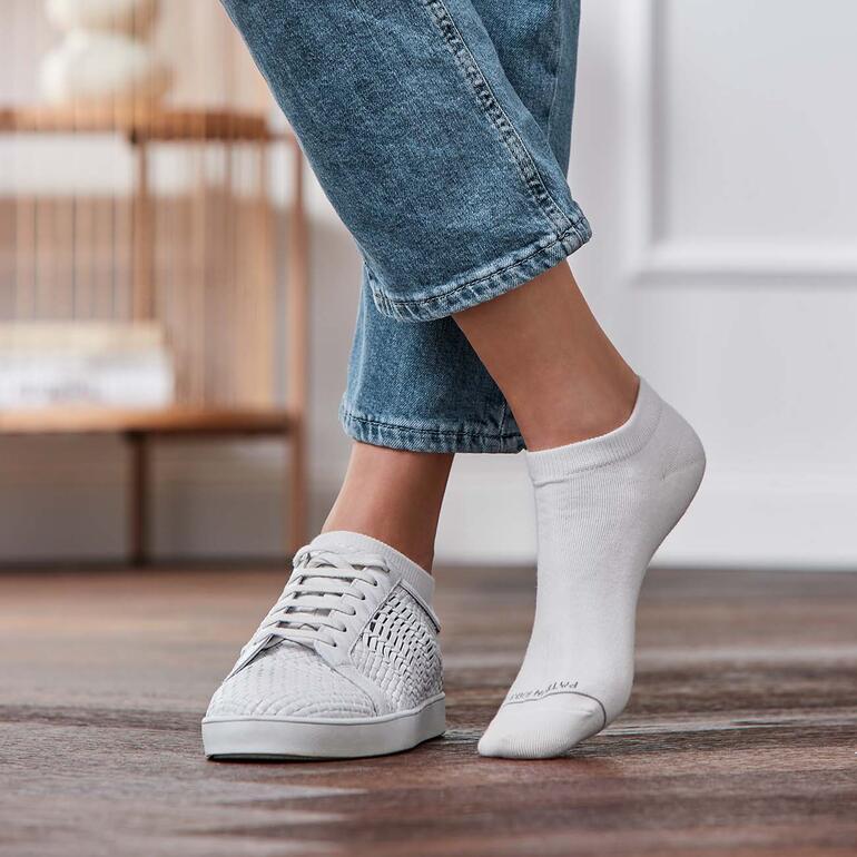 Blanc Pieds dans des baskets avec une chaussette blanche visible sur un pied.