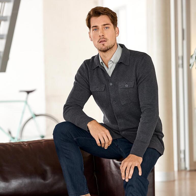 Anthracite Homme assis sur un canapé, portant un cardigan gris.