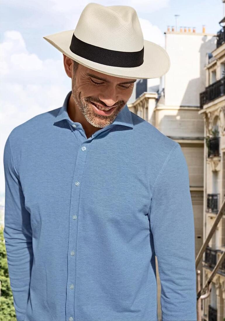 Homme avec un chapeau de Panama et une chemise bleu clair.
