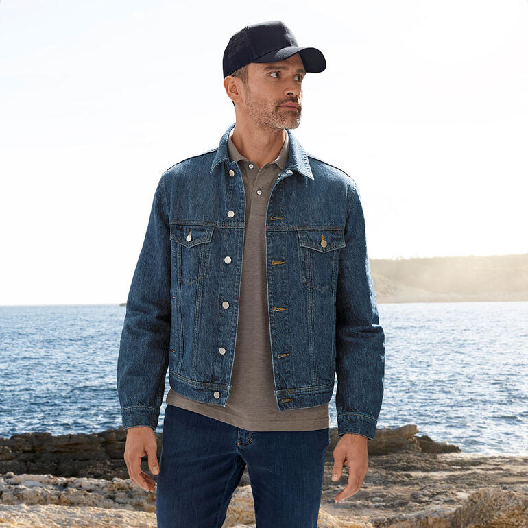Casquette Trucker Stetson Homme en veste en jean en chanvre OCONI au bord de la mer avec un polo gris.