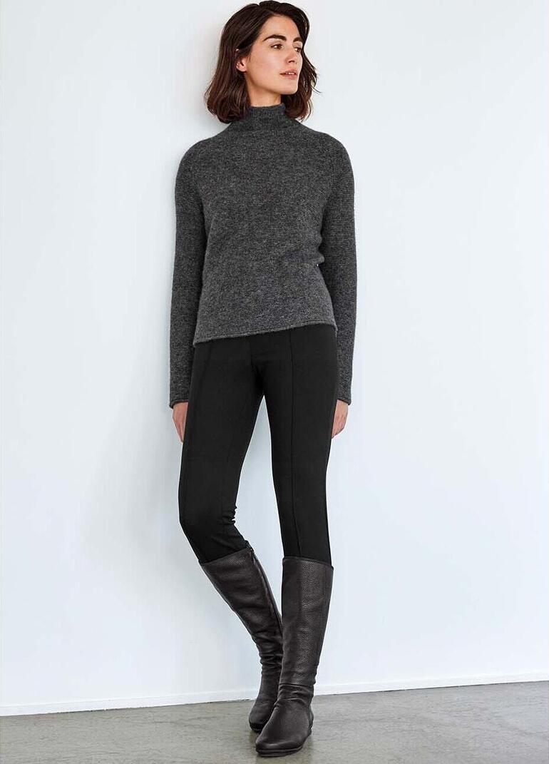 Gris Femme portant un pull boxy gris et des leggings noirs.