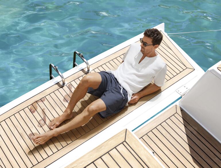 Short de bain Swim&Dry Homme en shorts blancs assis sur une jetée à côté d'une piscine.