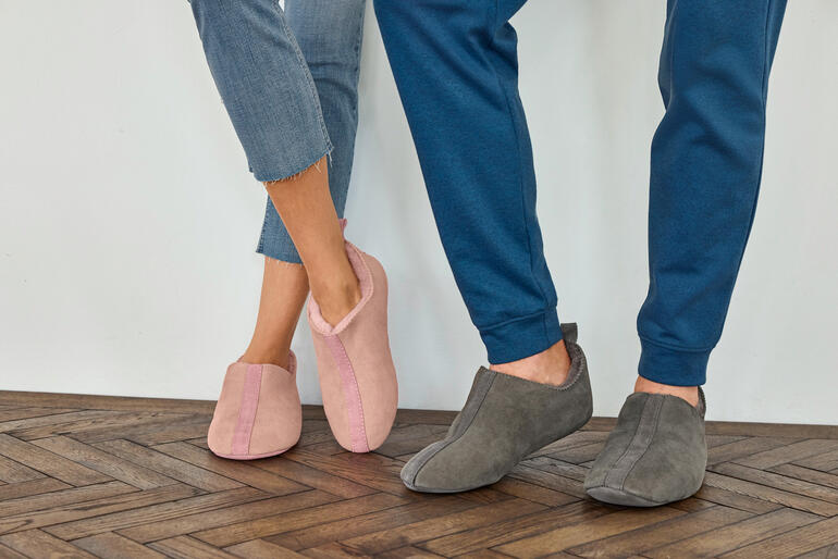 Femme, Rose et Homme, Gris Une paire de chaussons en laine d'agneau rose et gris sur le sol.