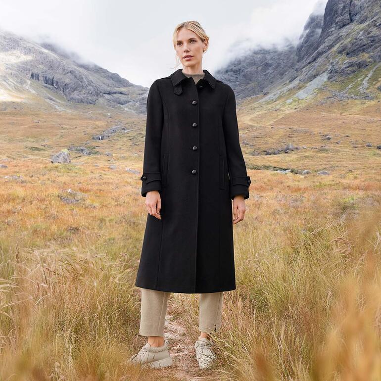 Manteau en loden alpaga noir de Steinbock, porté par une femme dans la nature.