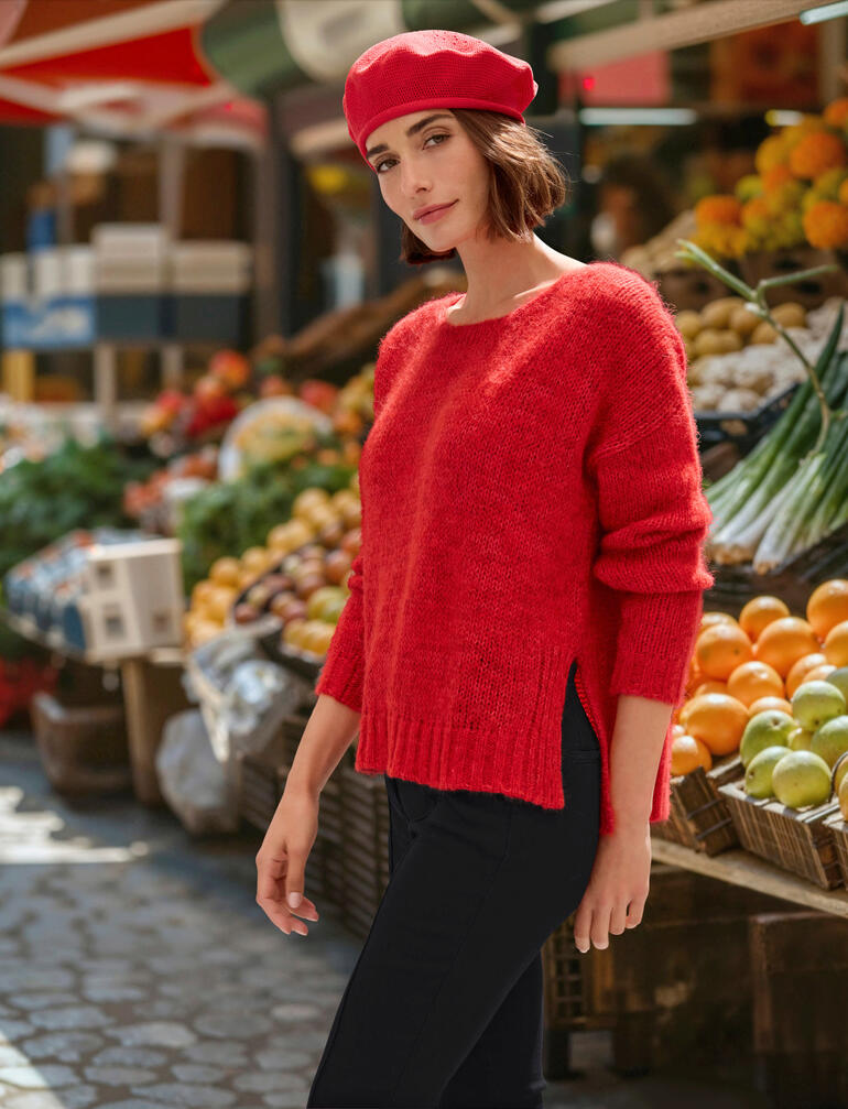 Femme portant un pull en alpaga rouge dans un marché