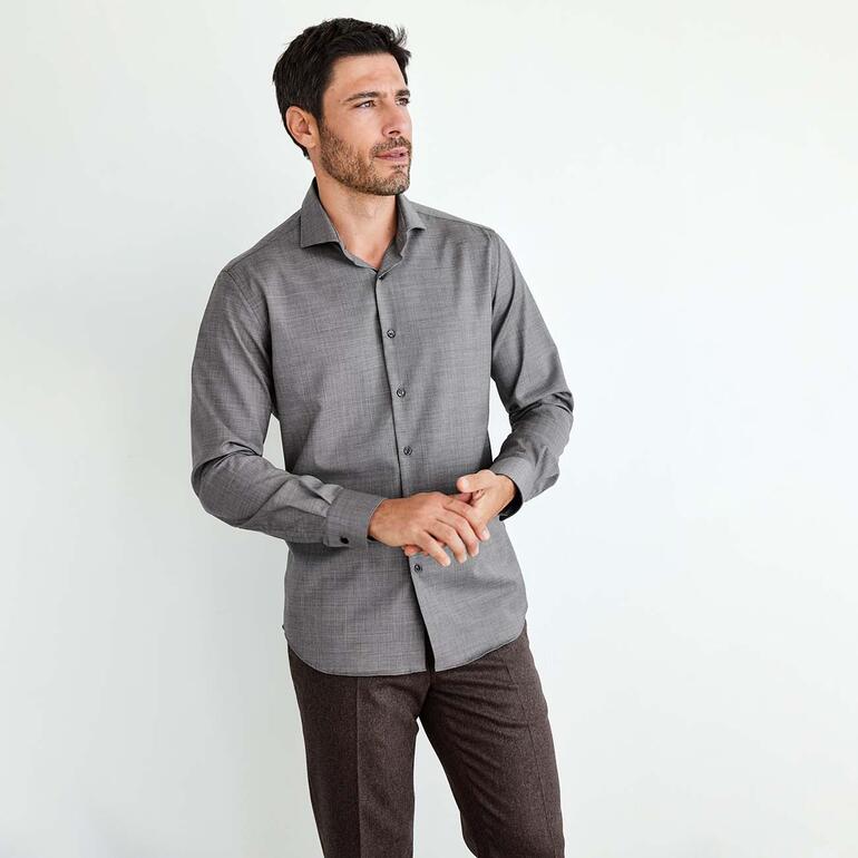 Chemise Performance en mérinos Homme en chemise Merino Performance grise debout dans une pièce lumineuse.