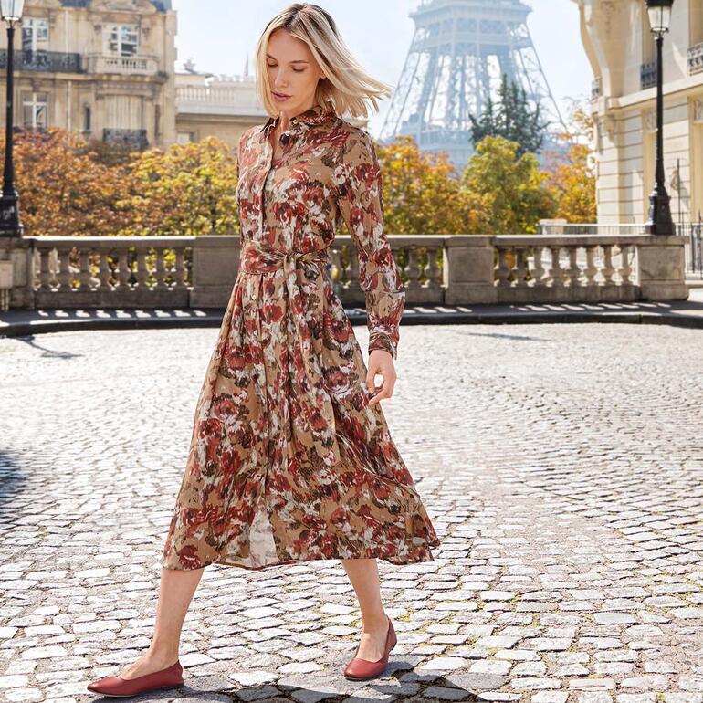 Robe laine et soie Rossana Diva, imprimé floral Femme en robe en laine et soie à motifs floraux, marchant sur des pavés.