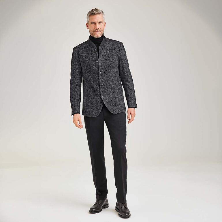 Chaussures dʼaffaire en peau de daim Homme en tenue noire avec des chaussures de ville en cuir, debout sur un fond neutre.