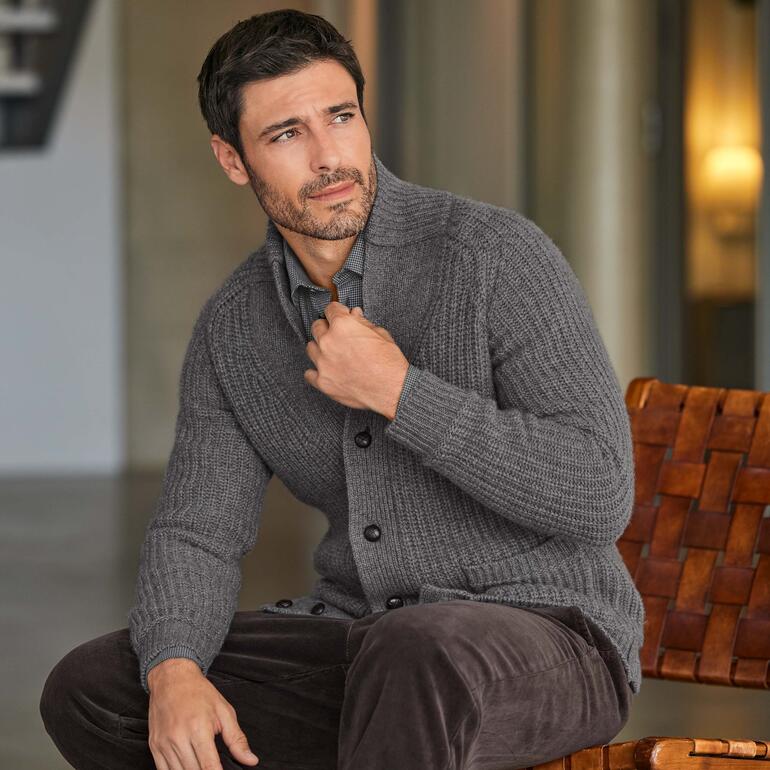 Homme en cardigan en cachemire gris, souriant légèrement.