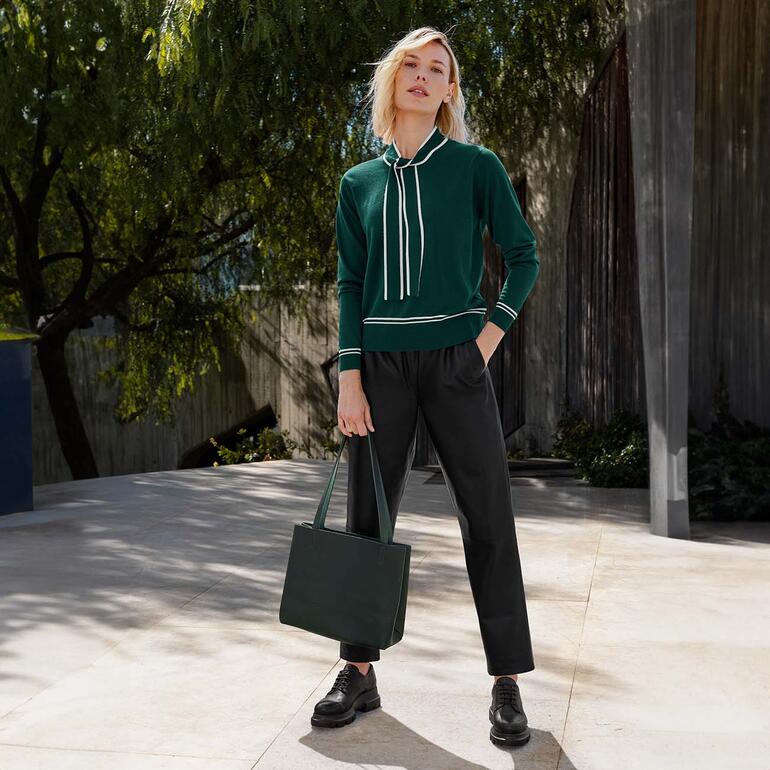 Femme en chemisier vert associé à un pantalon noir.