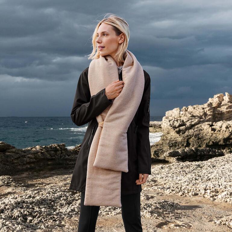 Écharpe rembourrée double-face Femme portant une écharpe double face matelassée beige sur la plage.