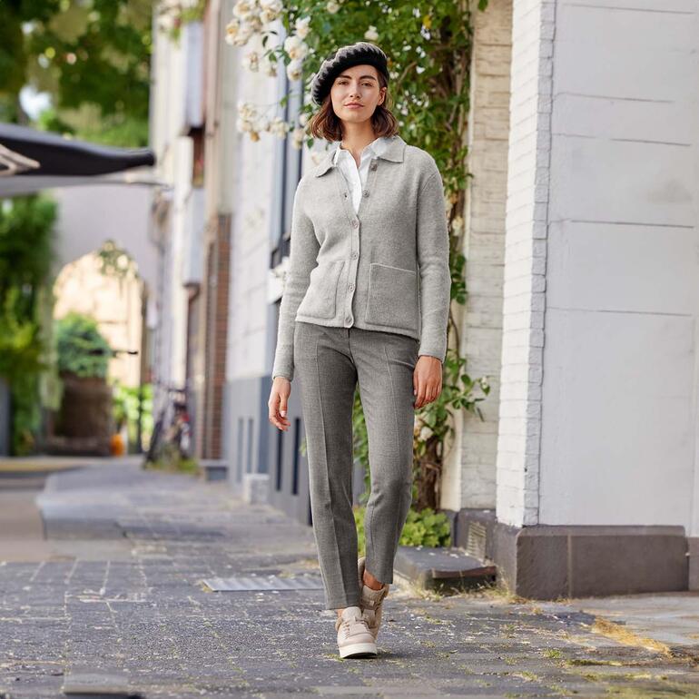 Cardigan Feel-Good Junghans 1954 Femme en cardigan Feel-Good gris avec un béret, se tenant dans une rue de la ville.