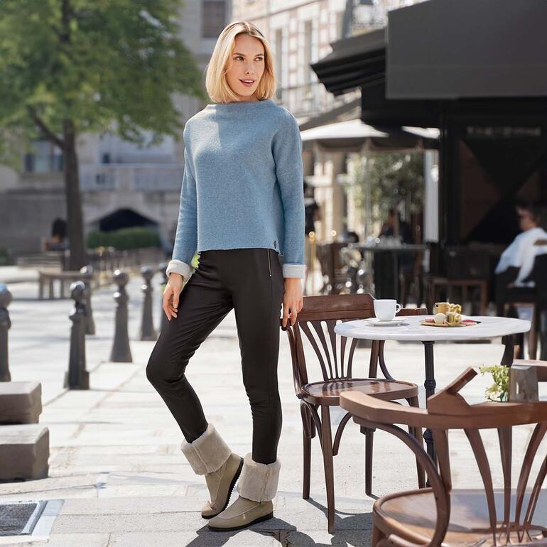 Bottes en peau dʼagneau double-face arche Femme en pull bleu clair et bottes en agneau assise à l'extérieur.